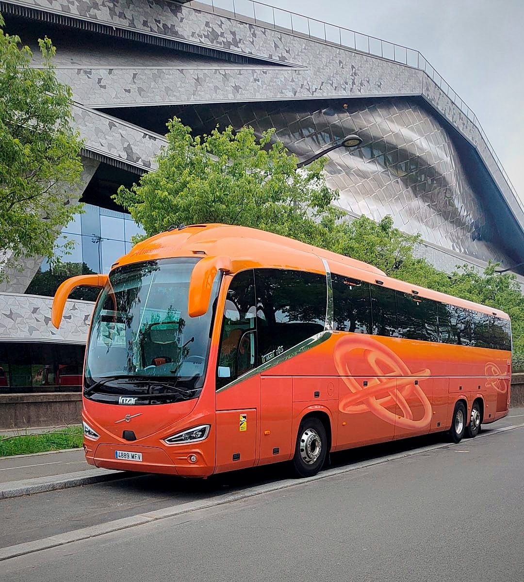 Autocar de Kapital Bus ante un edificio de arquitectura contemporánea